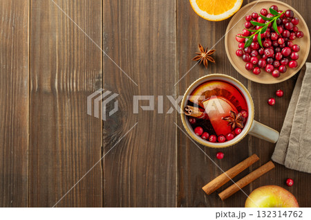 A mulled wine in a mug with cinnamon, berries and fruits on a dark wooden background. 132314762