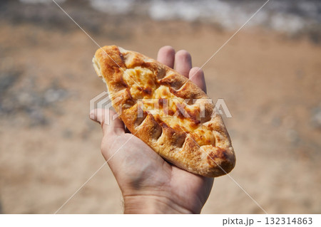 Pie with cottage cheese filling in the hand of a man outdoors 132314863
