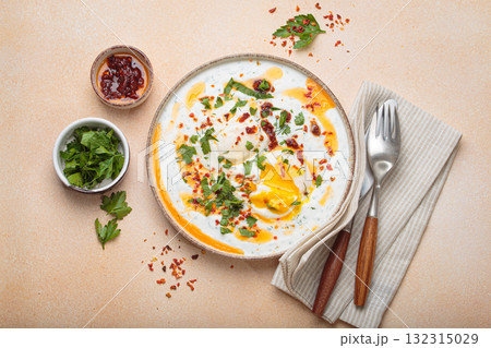 Turkish eggs cilbir, Middle Eastern style breakfast on beige background table top view 132315029