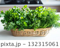 Brightly lit kitchen countertop features a basket filled with fresh parsley, cilantro, and dill, inviting culinary creativity and adding a touch of freshness to meal preparation 132315061