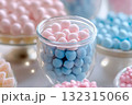 A beautifully arranged dessert table features glass jars filled with pink and blue candies. The detailed focus highlights the vibrant colors, perfect for a gender reveal celebration 132315066