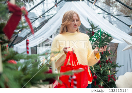 Thoughtful blonde woman holding red shopping bags during Christmas holidays 132315134