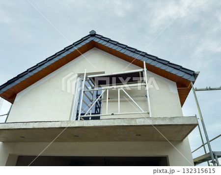 Building renovation project showcasing scaffolding under a cloudy sky outside a newly constructed home in a suburban area Building renovation project showcasing scaffolding under a cloudy sky outside a newly constructed home in a suburban area 132315615