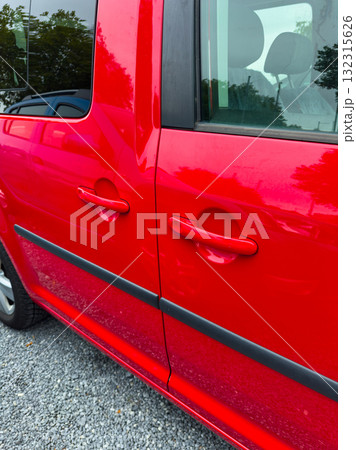 Bright red vehicle parked on gravel, showcasing its glossy finish and sleek lines in the afternoon light 132315626