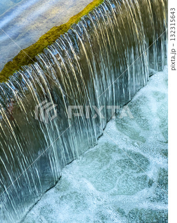 Water cascades gently over a stone ledge creating a soothing, natural soundscape near a tranquil stream in the heart of nature Water cascades gently over a stone ledge creating a soothing, natural soundscape near a tranquil stream in the heart of nature 132315643