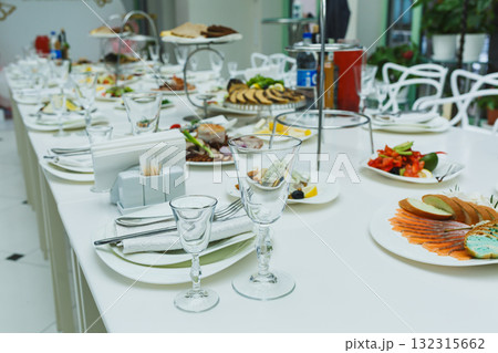 Elegant buffet table featuring an array of delicious dishes in a bright, modern venue during a lively gathering Elegant buffet table featuring an array of delicious dishes in a bright, modern venue during a lively gathering 132315662