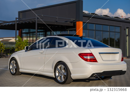 A Sleek White Sports Car is Parked Elegantly Outside an Impressive Modern Architectural Design, Showcasing the Intersection of Stylish Automobile Design and Contemporary Engineering Mastery 132315668