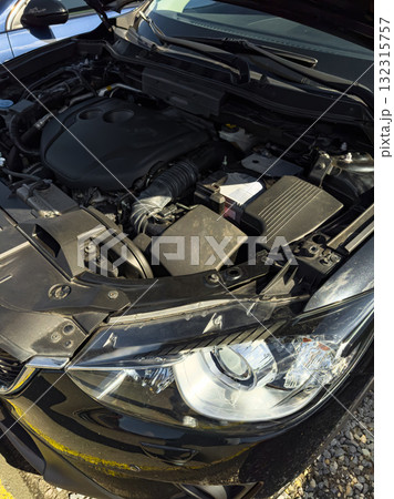 Under the hood of a sleek black car showcasing the intricate components of modern automotive design and engineering at a sunny parking lot Under the hood of a sleek black car showcasing the intricate components of modern automotive design and engineering at a sunny parking lot 132315757