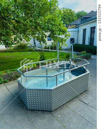 Relaxing outdoor hot tub surrounded by greenery on a sunny day 132315794