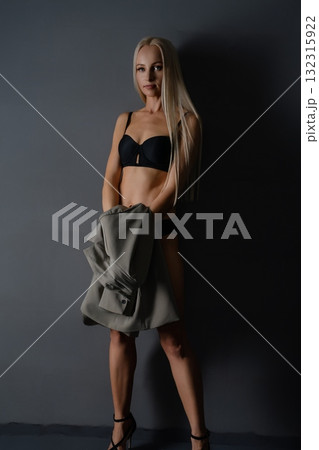 A confident woman in stylish attire poses against a dark backdrop 132315922