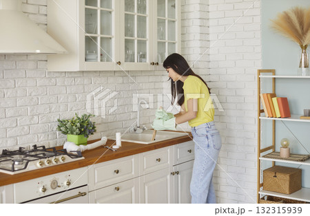 Woman in rubber gloves unclogging kitchen sink drain with plunger at home Woman in rubber gloves unclogging kitchen sink drain with plunger at home 132315939