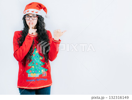 Girl in Christmas sweater and glasses pointing to the side, isolated. Young woman in Christmas hat making secret gesture recommending an advertisement Girl in Christmas sweater and glasses pointing to the side, isolated. Young woman in Christmas hat making secret gesture recommending an advertisement 132316149