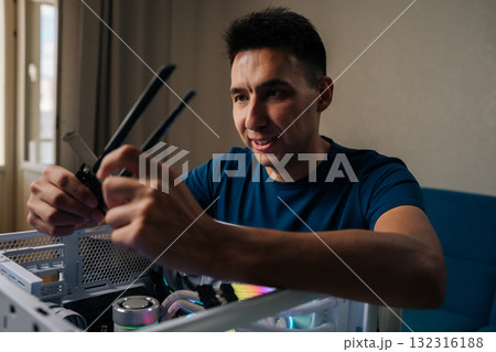 Positive computer technician male inserting wireless network module inside custom desktop computer, enhancing system connectivity for reliable internet performance. Concept of modern technology Positive computer technician male inserting wireless network module inside custom desktop computer, enhancing system connectivity for reliable internet performance. Concept of modern technology 132316188