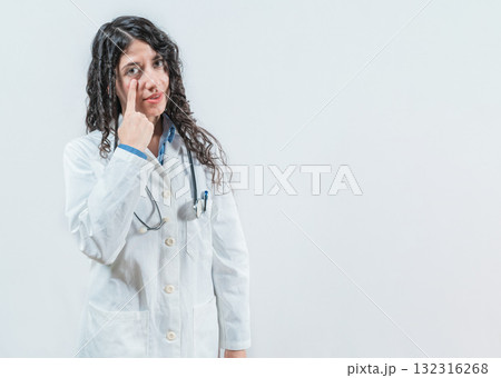 Suspicious young doctor pointing at eye, isolated. Suspicious female doctor looking you isolated 132316268