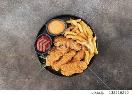 Crispy chicken breast strips with ketchup and cheese sause on a dark background. Top view. Fast food Crispy chicken breast strips with ketchup and cheese sause on a dark background. Top view. Fast food 132316290