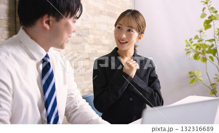 オフィスでパソコンを見ながら打ち合わせをする若い男女 132316689