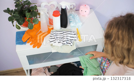 Teen girl folds laundry and tidies bedroom keeping it clean and organized Teen girl folds laundry and tidies bedroom keeping it clean and organized 132317318