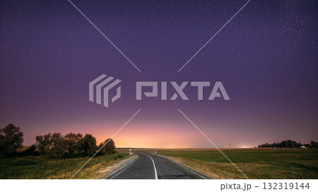 Night Starry Sky Above Country Road In Countryside And Green Field. Yellow City Lights On Background. Night View Of Natural Glowing Stars Night Starry Sky Above Country Road In Countryside And Green Field. Yellow City Lights On Background. Night View Of Natural Glowing Stars 132319144