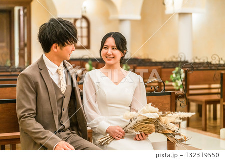 結婚式場,チャペルのベンチに座る新郎新婦(バージンロード・教会・チャペル) 結婚式場,チャペルのベンチに座る新郎新婦(バージンロード・教会・チャペル) 132319550