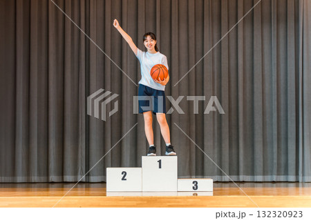 体育館のステージで表彰台に乗る体操着姿の小学生,中学生,高校生の女の子 132320923