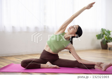 ヨガマットの上でヨガのポーズをするミドル女性 132321003