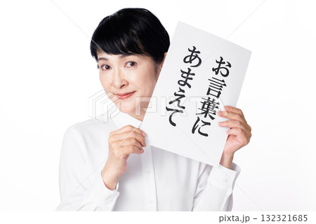 お言葉に甘えてと書かれた紙を持ち甘えた表情のシニア女性 お言葉に甘えてと書かれた紙を持ち甘えた表情のシニア女性 132321685