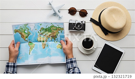 Traveler planning vacation looking at world map with travel accessories Traveler planning vacation looking at world map with travel accessories 132321719