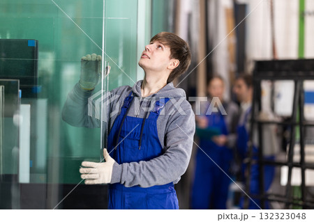 Young guy stacking glass sheets in factory Young guy stacking glass sheets in factory 132323048