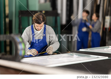 Man employee in blue overall measures given length of plastic material 132323080