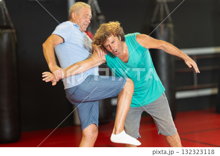 Middle-aged man enduring painful arm lock during training sparring 132323118