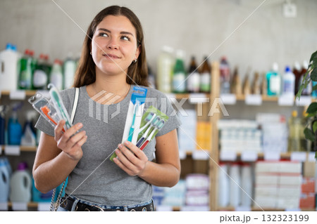 Young woman choosing toothbrush in store 132323199
