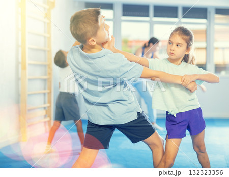 Boys and girls in gym perform basic elements of krav maga self-defense system. Boys and girls in gym perform basic elements of krav maga self-defense system. 132323356