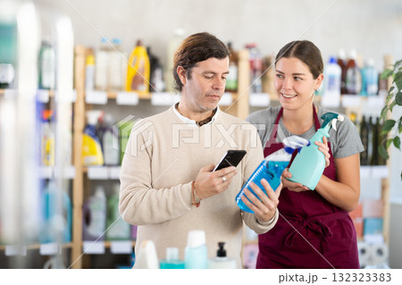 Man scanning bottle of cleaning spray with smartphone in store 132323383