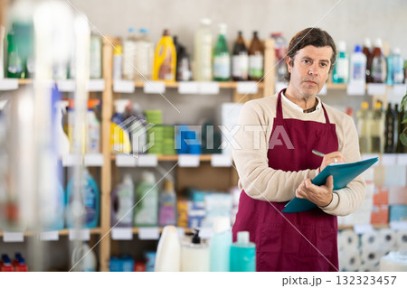 Man seller, with paper and invoice in hands, make inventory in store. 132323457