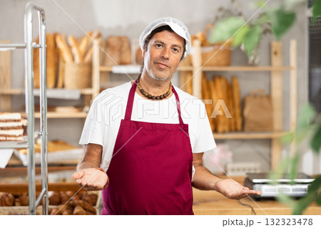 Middle-aged male seller stands in bake house, ready to greet customers 132323478