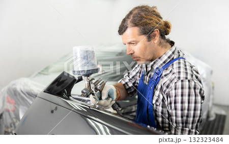Adult male mechanic paints car with machine 132323484