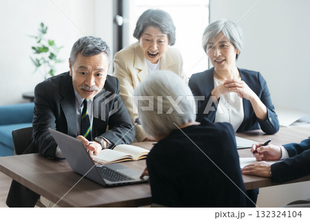 ノートパソコンを囲んで会議をするシニアチーム 132324104