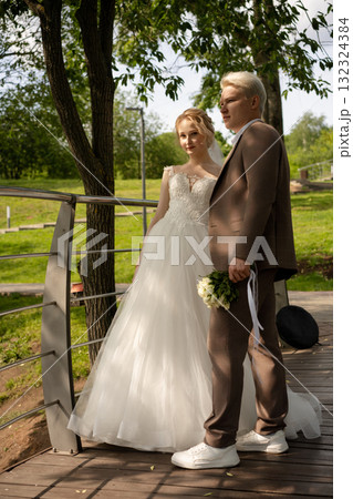 Couple celebrates wedding day on a bridge in a lush green park Couple celebrates wedding day on a bridge in a lush green park 132324384