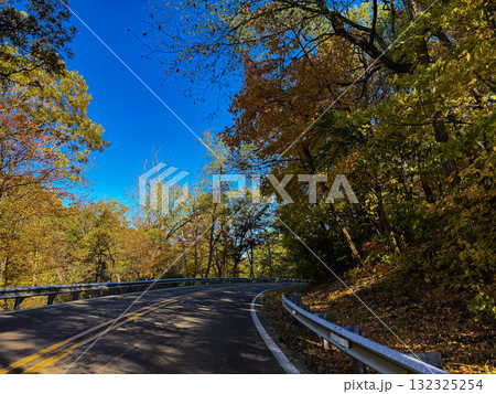 Scenic Curved Road Through Autumn Forest Under Clear Blue Sky Scenic Curved Road Through Autumn Forest Under Clear Blue Sky 132325254
