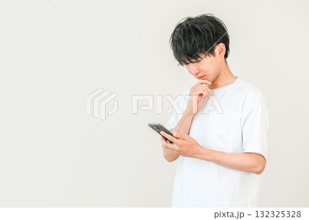 スマホを見ながら考える,検討する,悩む若いアジア人男性 スマホを見ながら考える,検討する,悩む若いアジア人男性 132325328