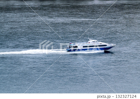 A pleasure boat with passengers sails along the river bank. 132327124