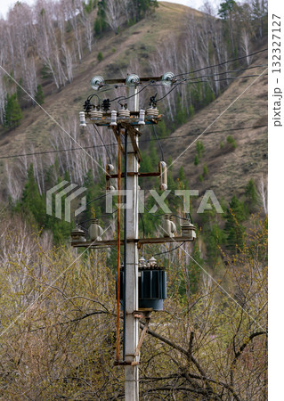 A concrete pole with power lines against a forest backdrop. 132327127