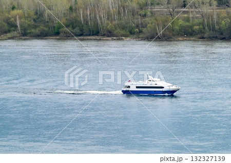A pleasure boat with passengers sails along the river bank. A pleasure boat with passengers sails along the river bank. 132327139