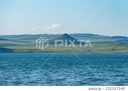 A mountain in the middle of a plain on the shore of a lake. A mountain in the middle of a plain on the shore of a lake. 132327140