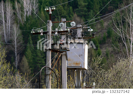 A concrete pole with power lines against a forest backdrop. A concrete pole with power lines against a forest backdrop. 132327142