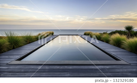 Serenity at sunset with a tranquil infinity pool overlooking the ocean and lush plants by the shore 132329180