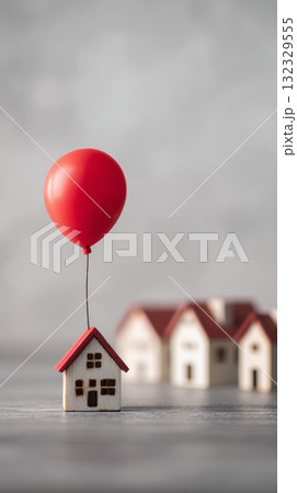 Miniature house with red balloon floating, symbolizing dream, hope, and real estate investment, with blurred houses in background 132329555