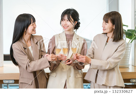 シャンパンを持ってオフィスに並ぶビジネスウーマン（チームワーク,決起集会,祝勝会,お祝い） 132330627