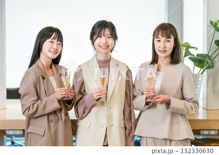 シャンパンを持ってオフィスに並ぶビジネスウーマン（チームワーク,決起集会,祝勝会,お祝い） 132330630