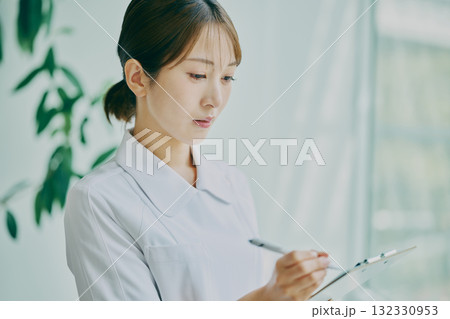 カルテを書き込む女性看護師 132330953